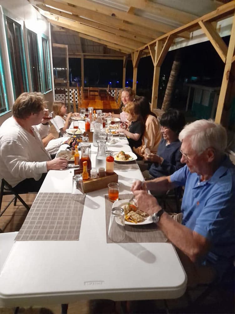 A group of people enjoying a festive dinner outdoors under a wooden structure.