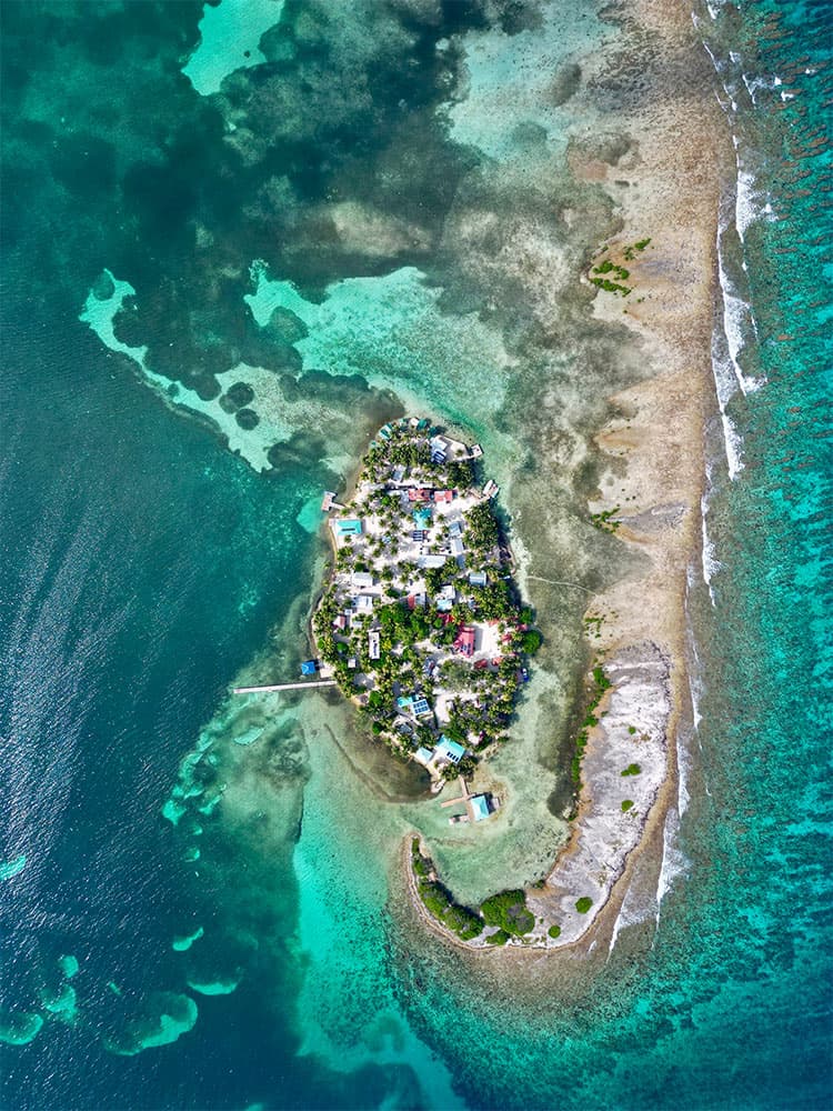 Aerial view of a small island surrounded by turquoise waters and coral reefs.