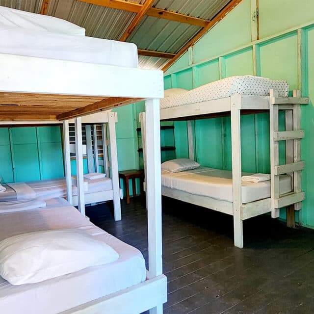 A simple dormitory with bunk beds and light blue walls.