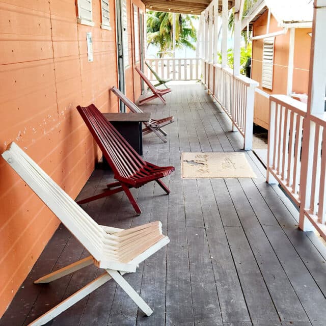 A porch with colorful wooden chairs and a welcome mat.