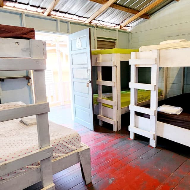 A cozy bedroom with two sets of bunk beds and a door leading outside.